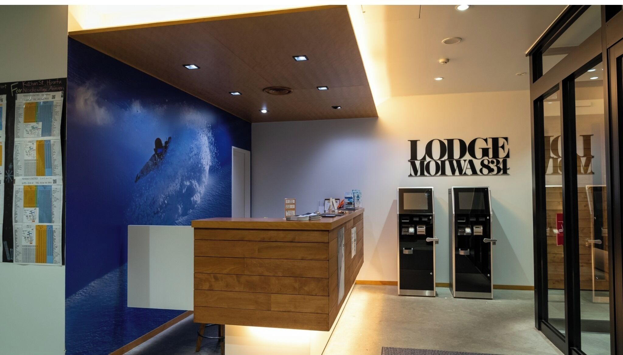 En receptionsdisk med träinredning, en blå vägg med en väggmålning med rymdtema och en skylt med texten ”Lodge Moiva 83”.