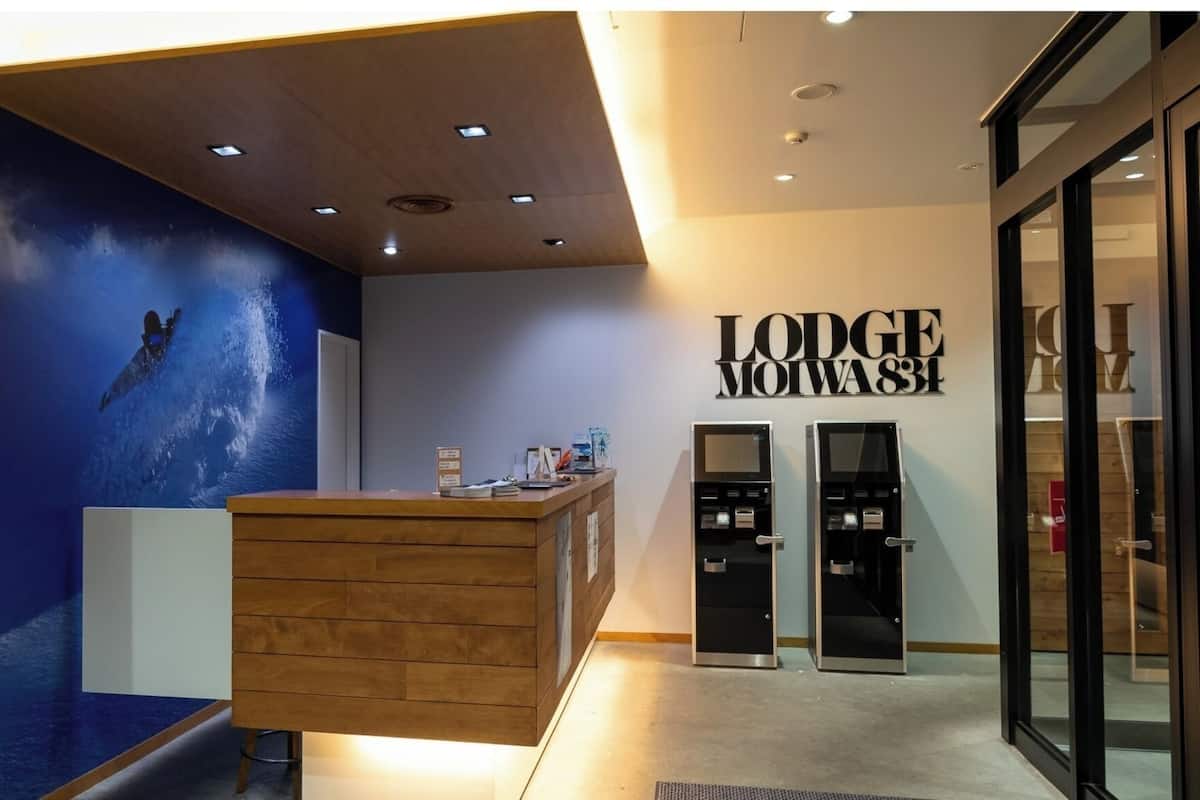 A reception desk with a wooden finish, a blue wall with a space-themed mural, and a sign reading 'Lodge Moiva 83'.