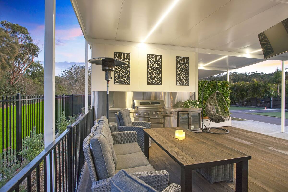 An outdoor kitchen area with a grill, seating, and a view of the surrounding landscape.