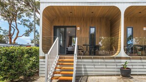 A modern building with a wooden exterior, a covered outdoor seating area, and a staircase leading to an entrance.