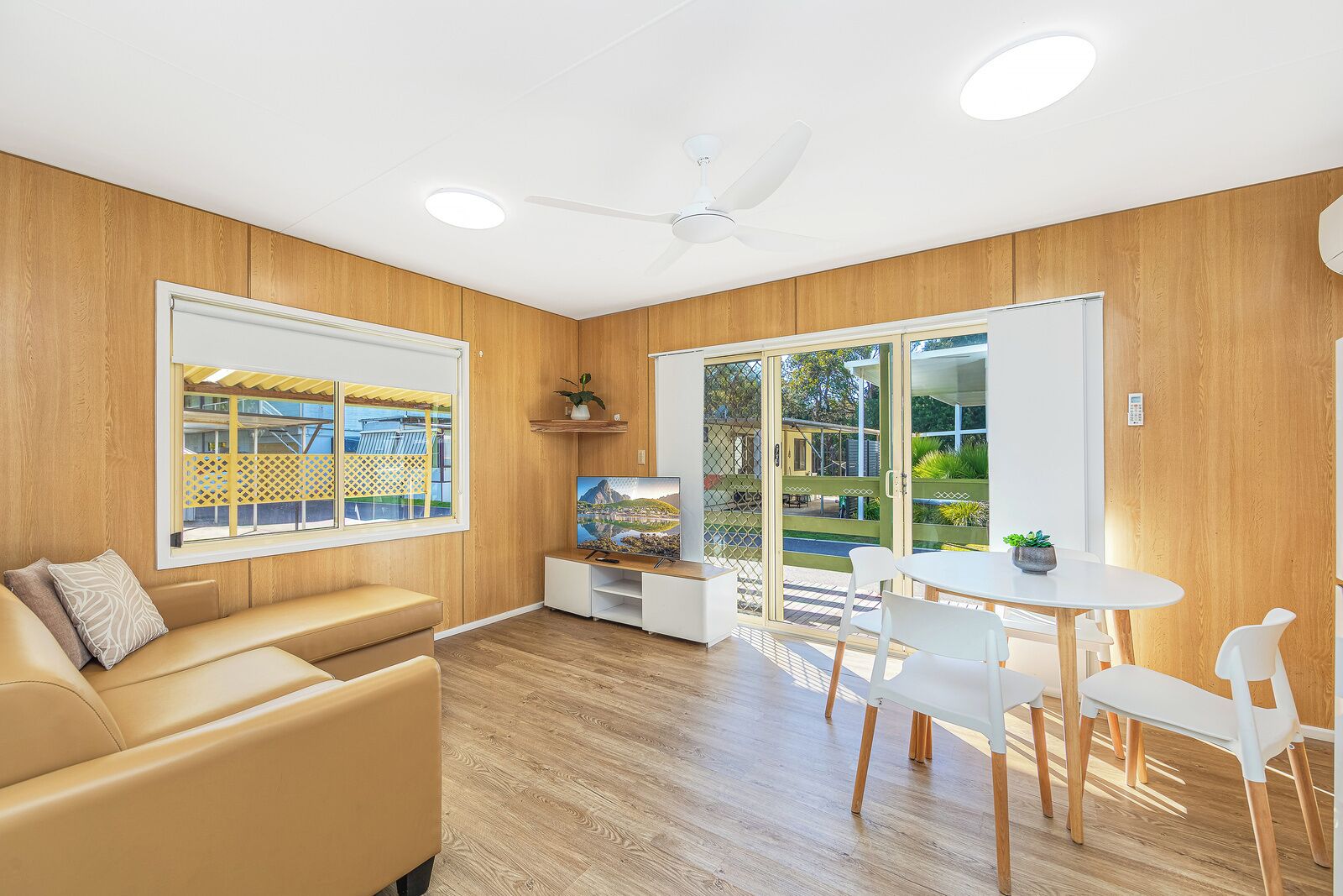 Uma sala de estar moderna com sofá, TV e área de jantar com cadeiras e mesa.
