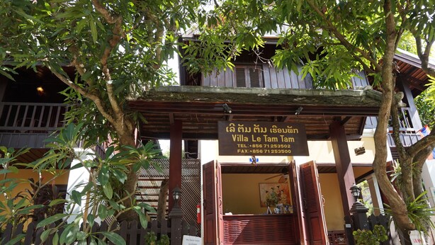 A traditional wooden villa with a signboard displaying its name and contact information.