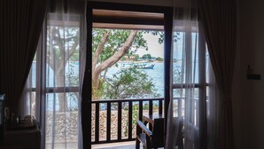 A room with a view of a body of water, a wooden deck, and a chair. - The C Samet Beach Resort (Rayong)