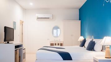 A modern hotel room with a bed, bedside lamps, a TV, a wardrobe, and an air conditioning unit.