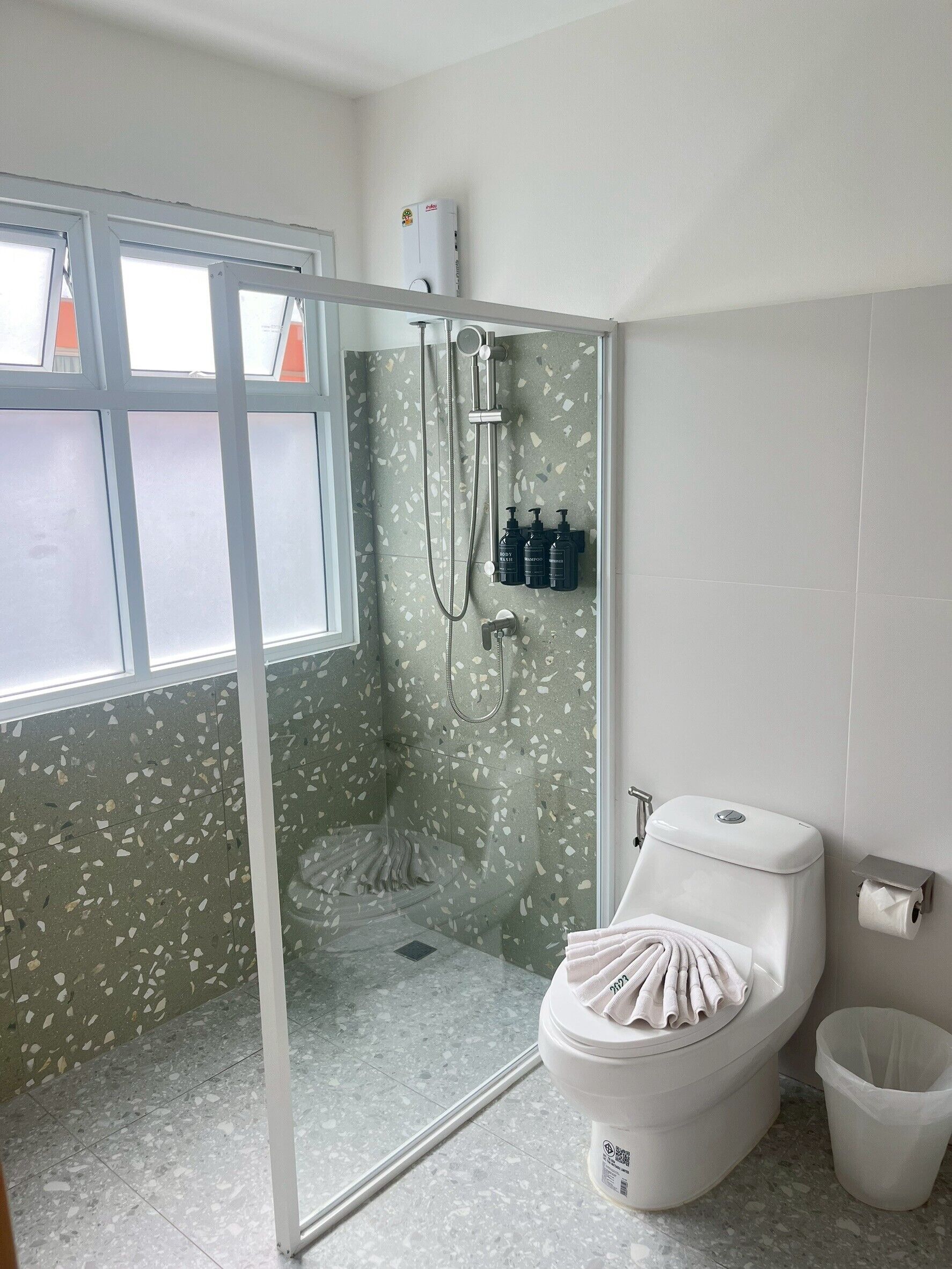 Ein Badezimmer mit Dusche, Toilette und einem Fenster.