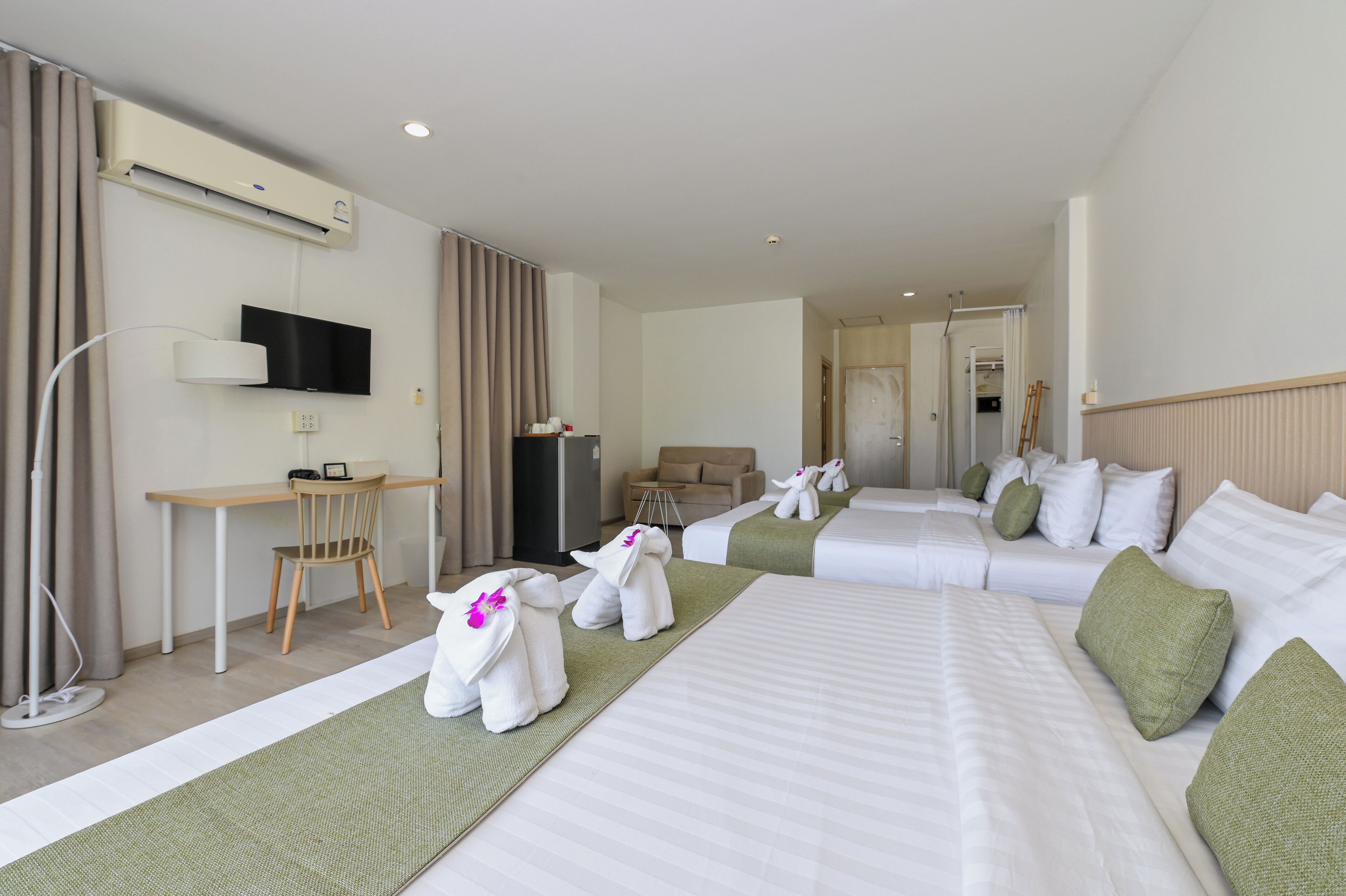 Habitación de hotel con cama, escritorio, silla, televisión y baño a la vista.