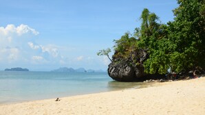 A beach with clear water, a sandy shore, and a large rock with trees. - Little Home Ao Nang (Krabi)