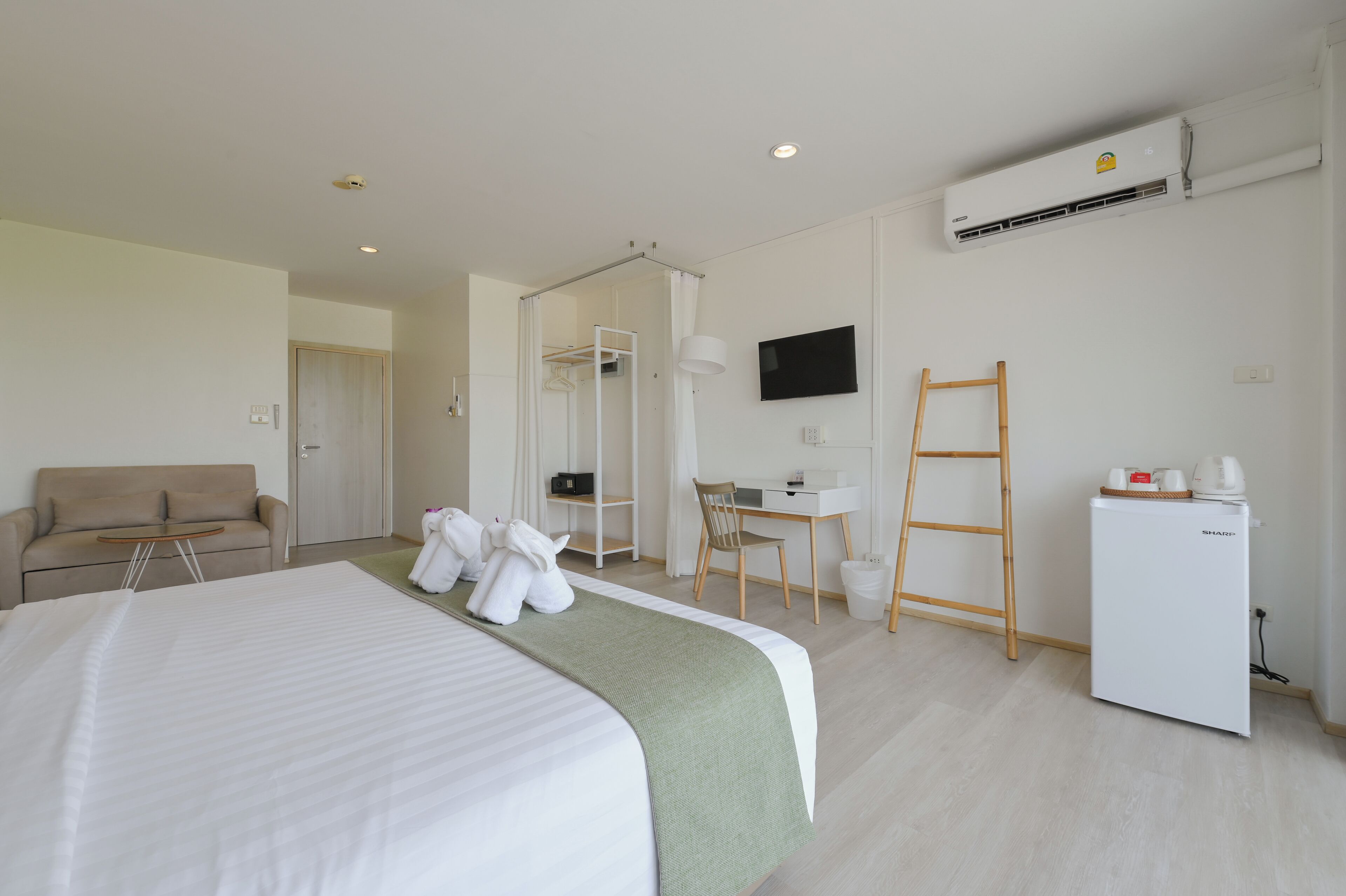 Une chambre d’hôtel équipée d’un lit, d’un bureau, d’une chaise, d’une armoire, d’un téléviseur et d’un appareil de climatisation.