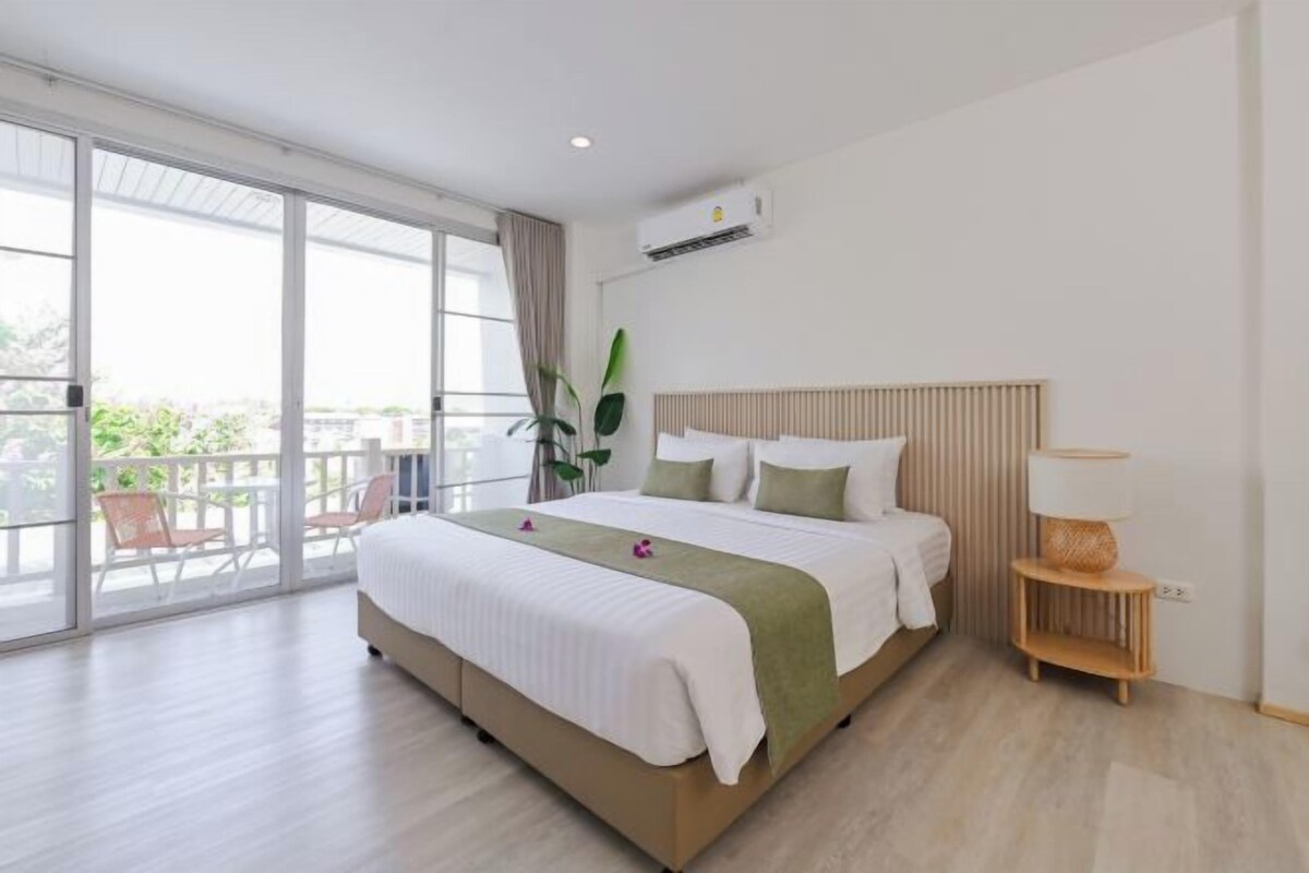 A modern hotel room with a large bed, a balcony, and a view of the outdoors.