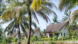 A serene lakeside view with traditional-style buildings, palm trees, and a calm water body reflecting the surroundings. - Khao Lak Blue Lagoon Resort (Takua Pa)