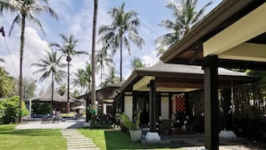 A pathway leading to covered outdoor seating areas with palm trees and a clear sky. - Khao Lak Blue Lagoon Resort (Takua Pa)
