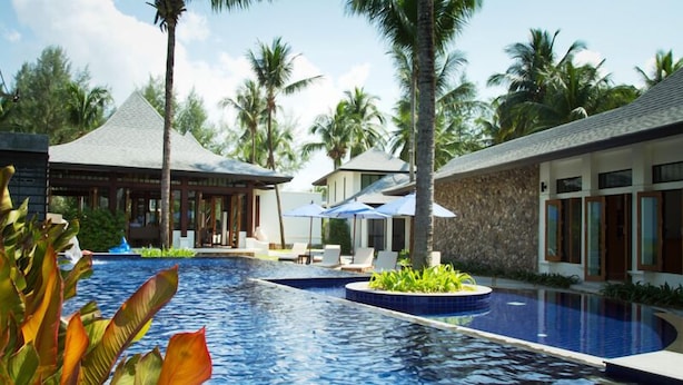 A resort pool area with lounge chairs, umbrellas, and palm trees. - Khao Lak Blue Lagoon Resort (Takua Pa)