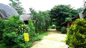 A pathway leading to a building surrounded by lush greenery. A sign indicates a quiet time after 10 PM.