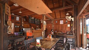 A rustic wooden interior with a wooden table and chairs, a chalkboard menu, and a fan.