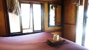 A room with a bed, a window with curtains, and a mirror on the wall.