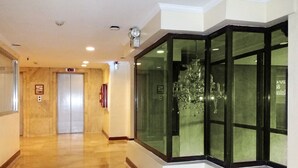 Ein Hotelkorridor mit poliertem Boden, einer Kristallleuchtre und einer Glastrennwand mit Blick.