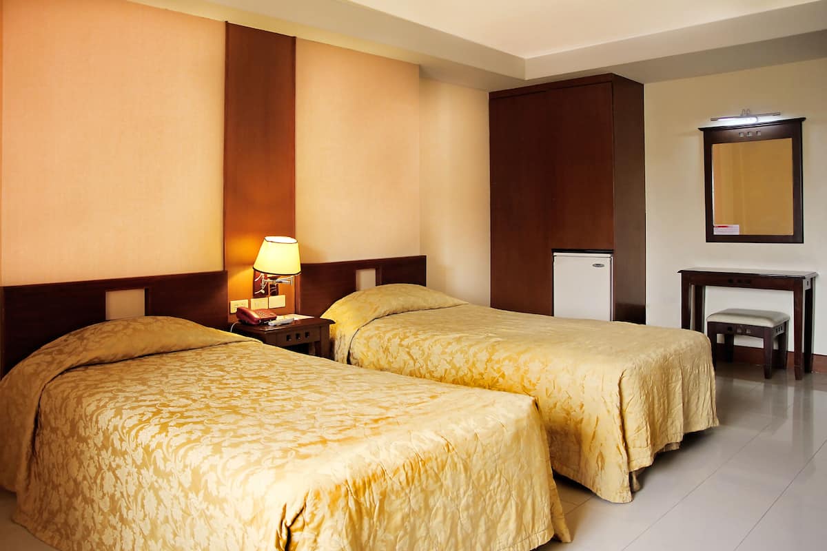 A hotel room with two beds, a desk, a chair, a lamp, and a mirror.