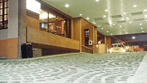 Eine Hotelhalle mit einem gemusterten Boden, einer Treppe und einem Fahrzeug im Hintergrund.