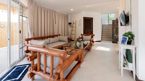 Een moderne woonkamer met een bank, salontafel en een televisie op een standaard.