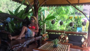 Un banco y una mesa de madera en un entorno tropical con abundante follaje.