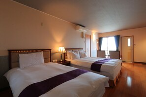 Une chambre d’hôtel avec deux lits, une table de chevet avec une lampe, une fenêtre avec des rideaux et un appareil de climatisation.