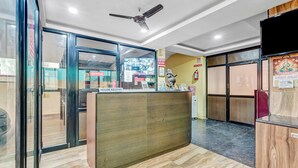 A reception area with a wooden reception desk, glass doors, a ceiling fan, and a fire extinguisher on the wall.