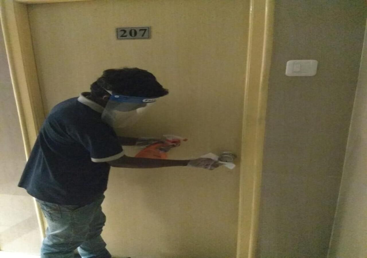 A person in a blue shirt and jeans standing in front of a door with the number 207.