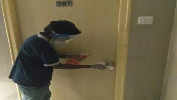 A person in a blue shirt and jeans standing in front of a door with the number 207.