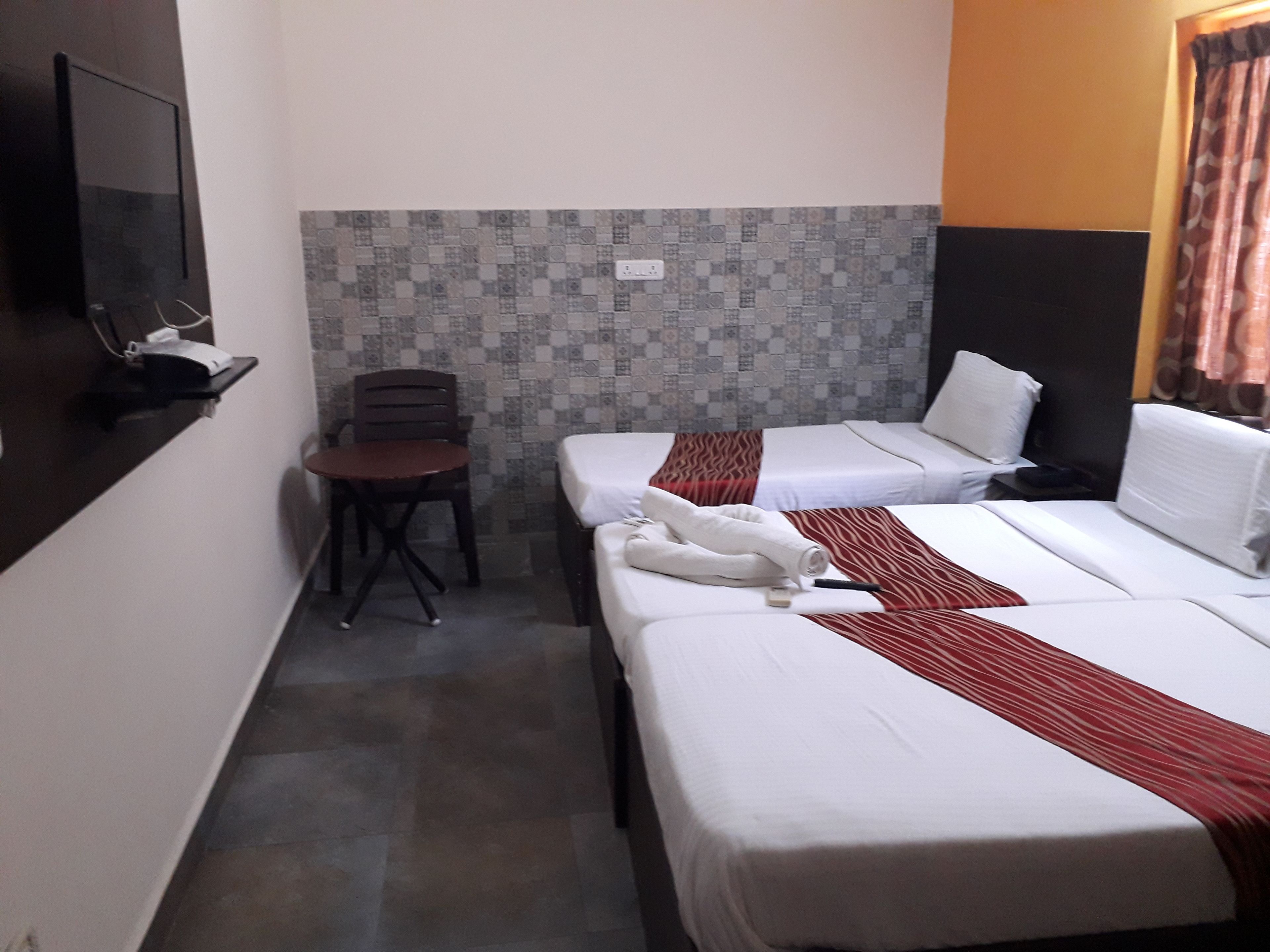 A hotel room with two beds, a small table, and a chair.