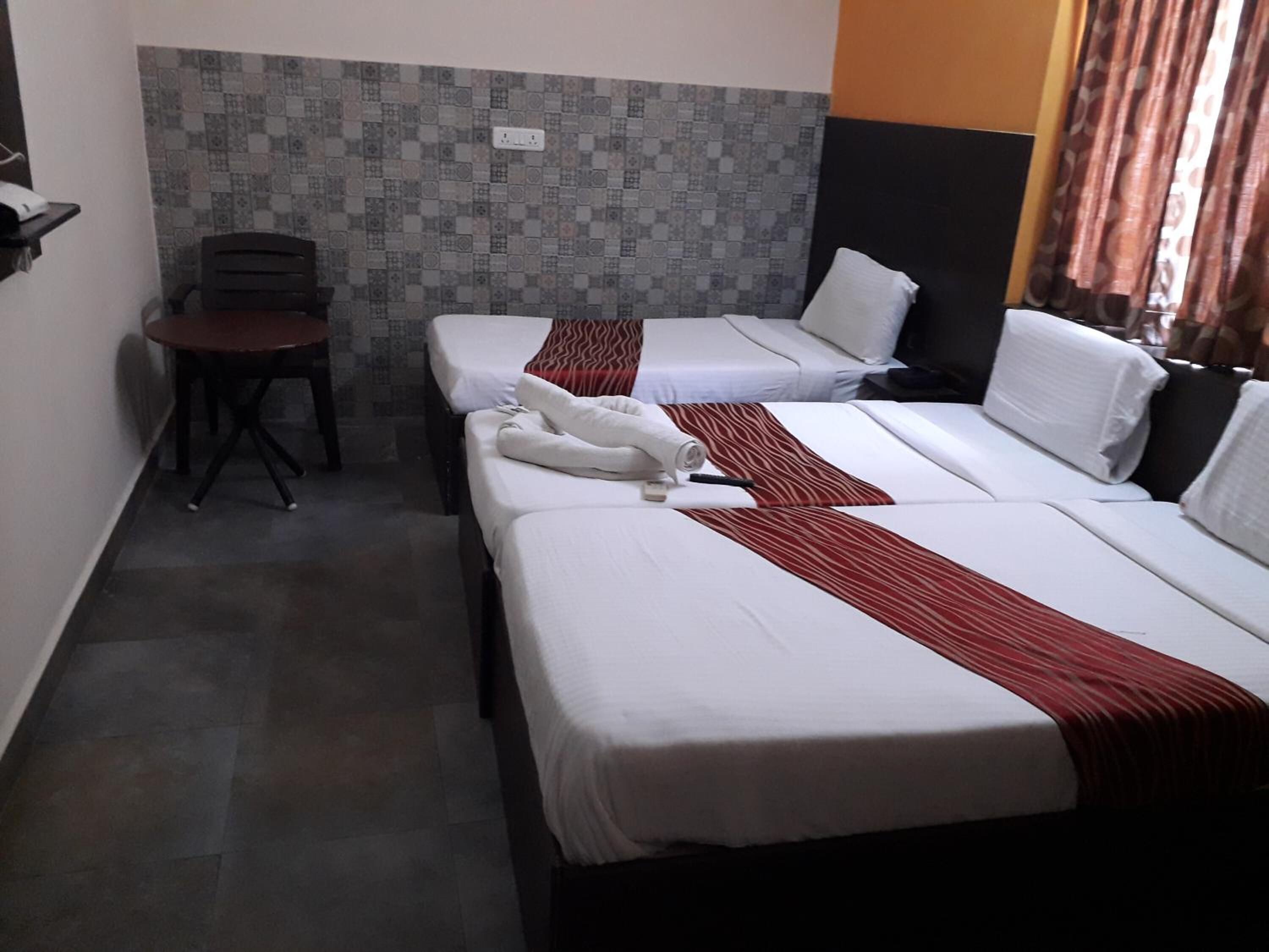 A hotel room with two beds, a small table, and a chair.