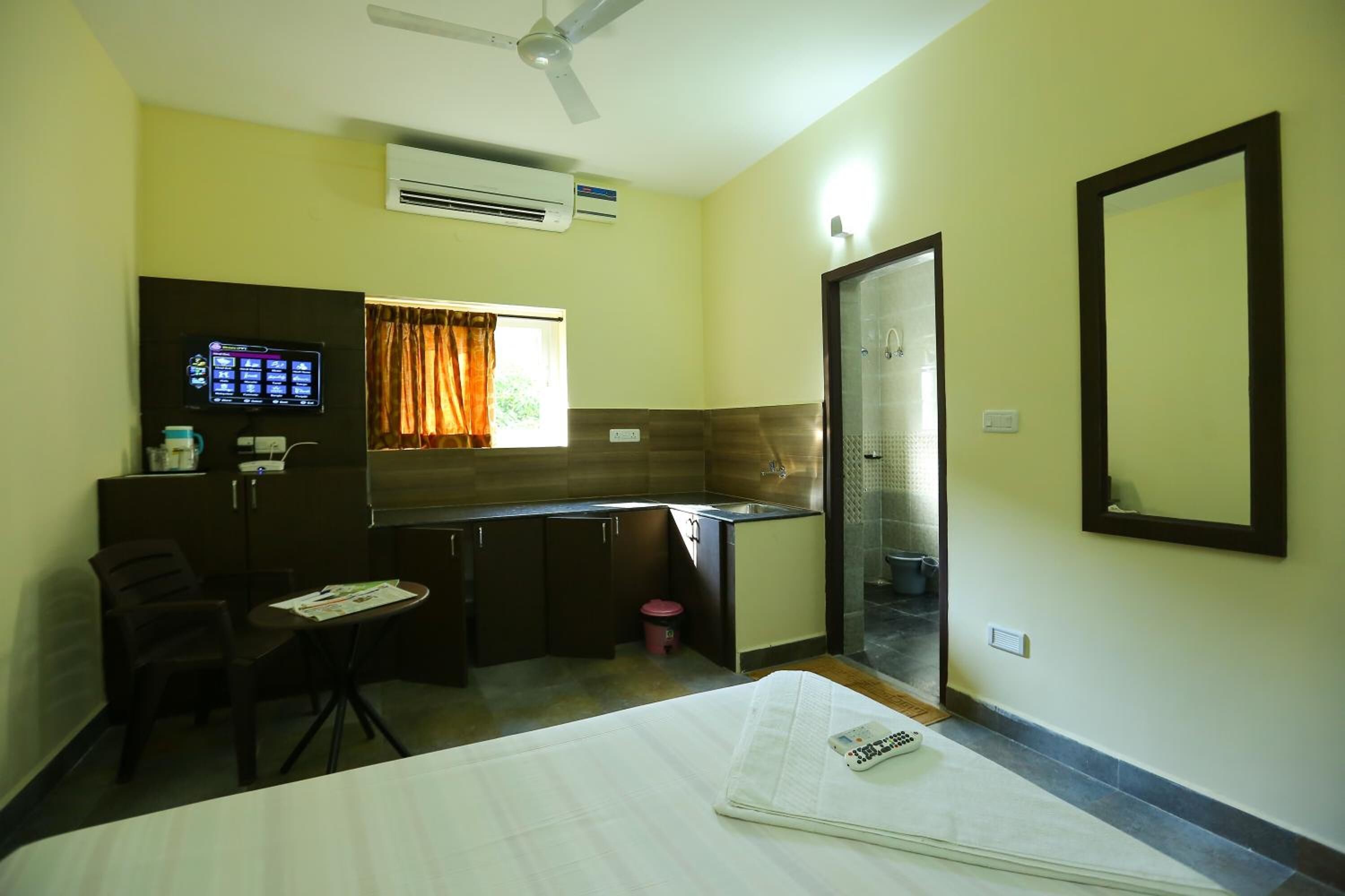 Une chambre d’hôtel de taille réduite, comprenant un lit, un petit bureau, une chaise, une télévision et une kitchenette.