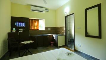 Une chambre d’hôtel de taille réduite, comprenant un lit, un petit bureau, une chaise, une télévision et une kitchenette.
