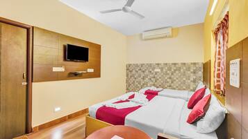 A hotel room with two beds, a television, a ceiling fan, and an air conditioning unit.