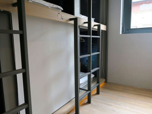 A bunk bed with a ladder, a closet with a hanging rod, and a window with a view of the outside. - Taipei Discover Hostel (Taipei)