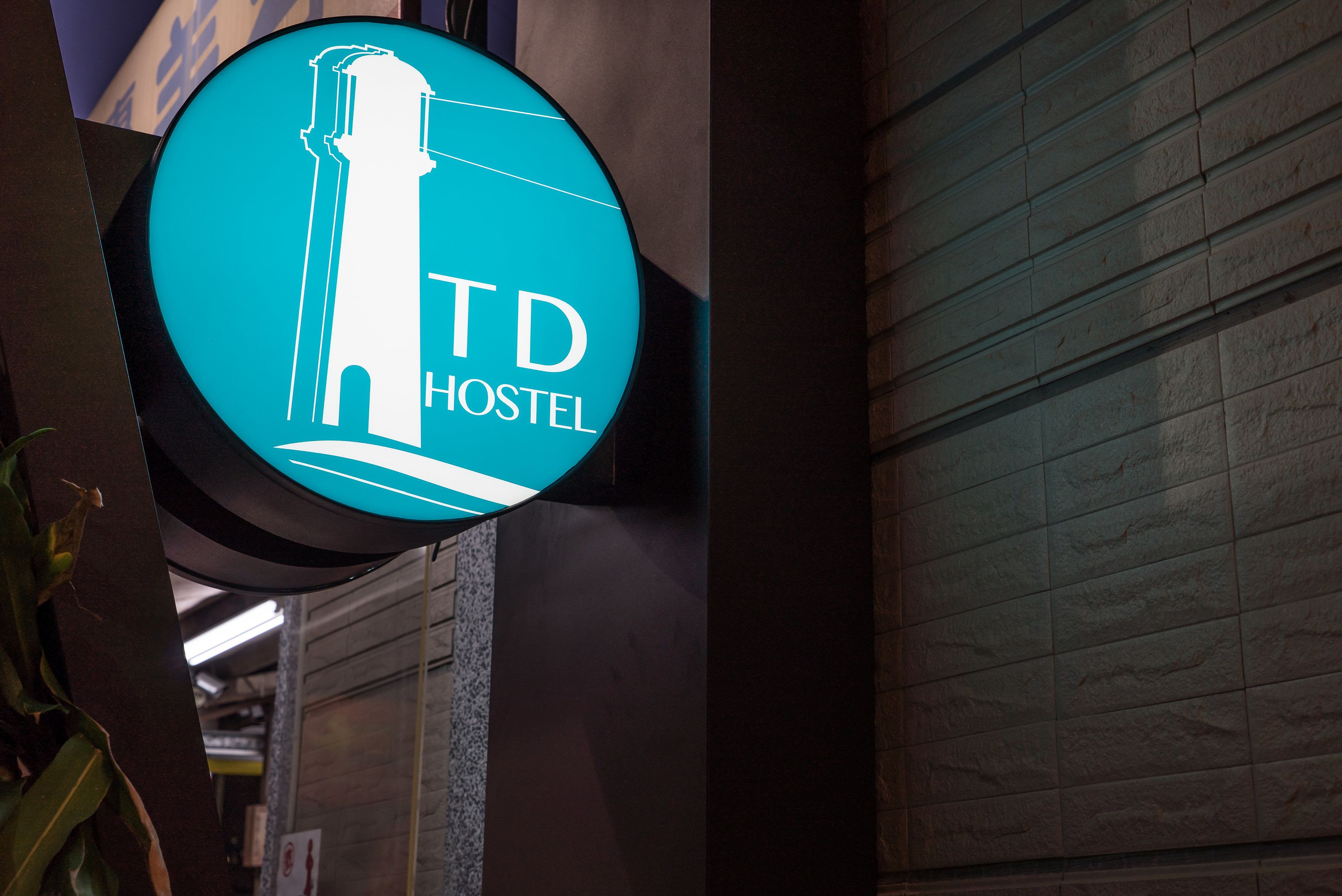 A neon sign for TD Hostel with a silhouette of a building.