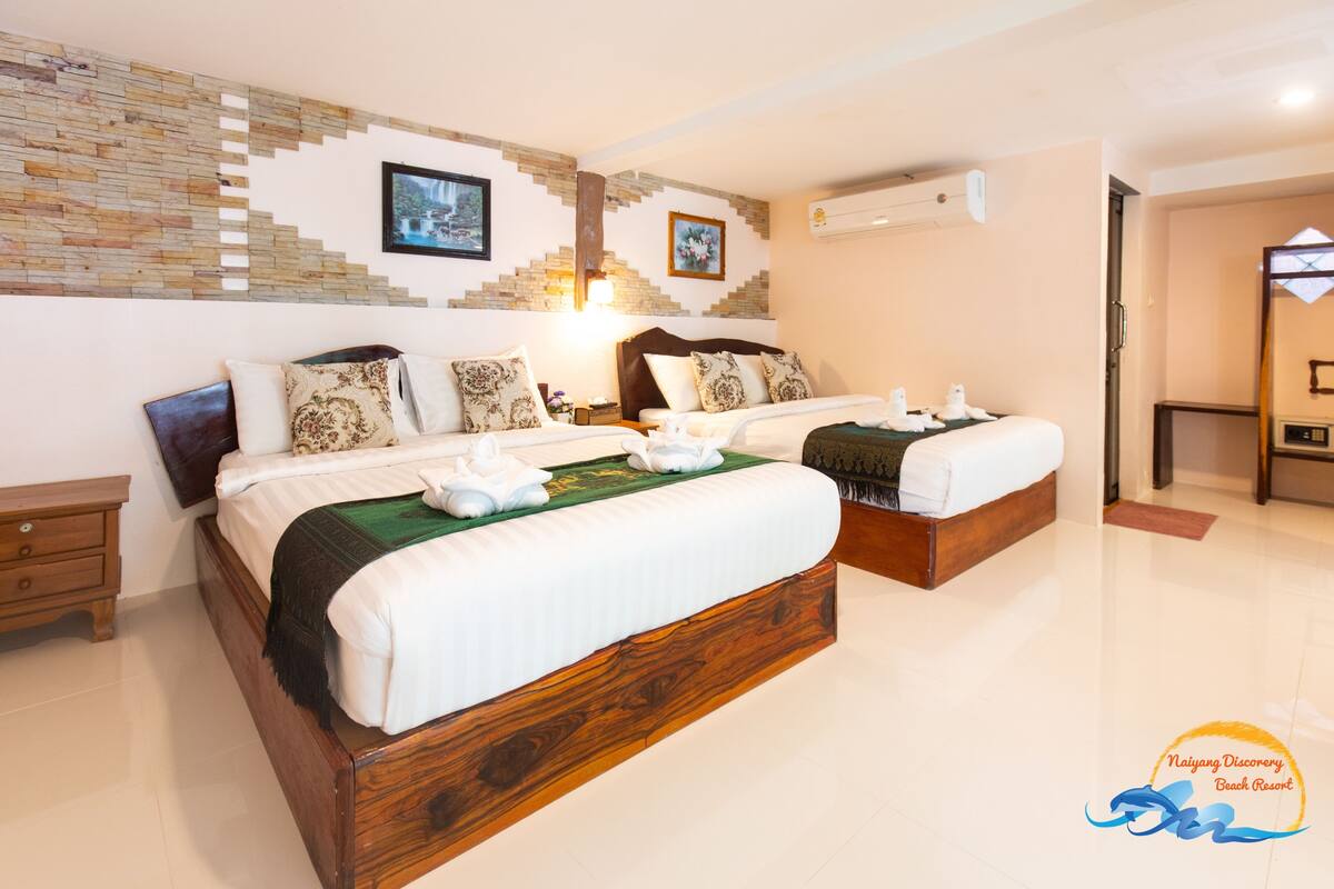 Habitación de hotel con dos camas de madera, un detalle decorativo en la pared y un cuadro enmarcado.
