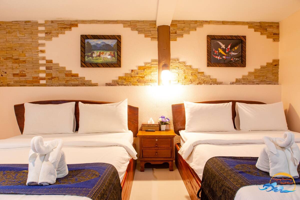 Una habitación de hotel con dos camas, una mesita de noche con lámpara y obras de arte en las paredes.