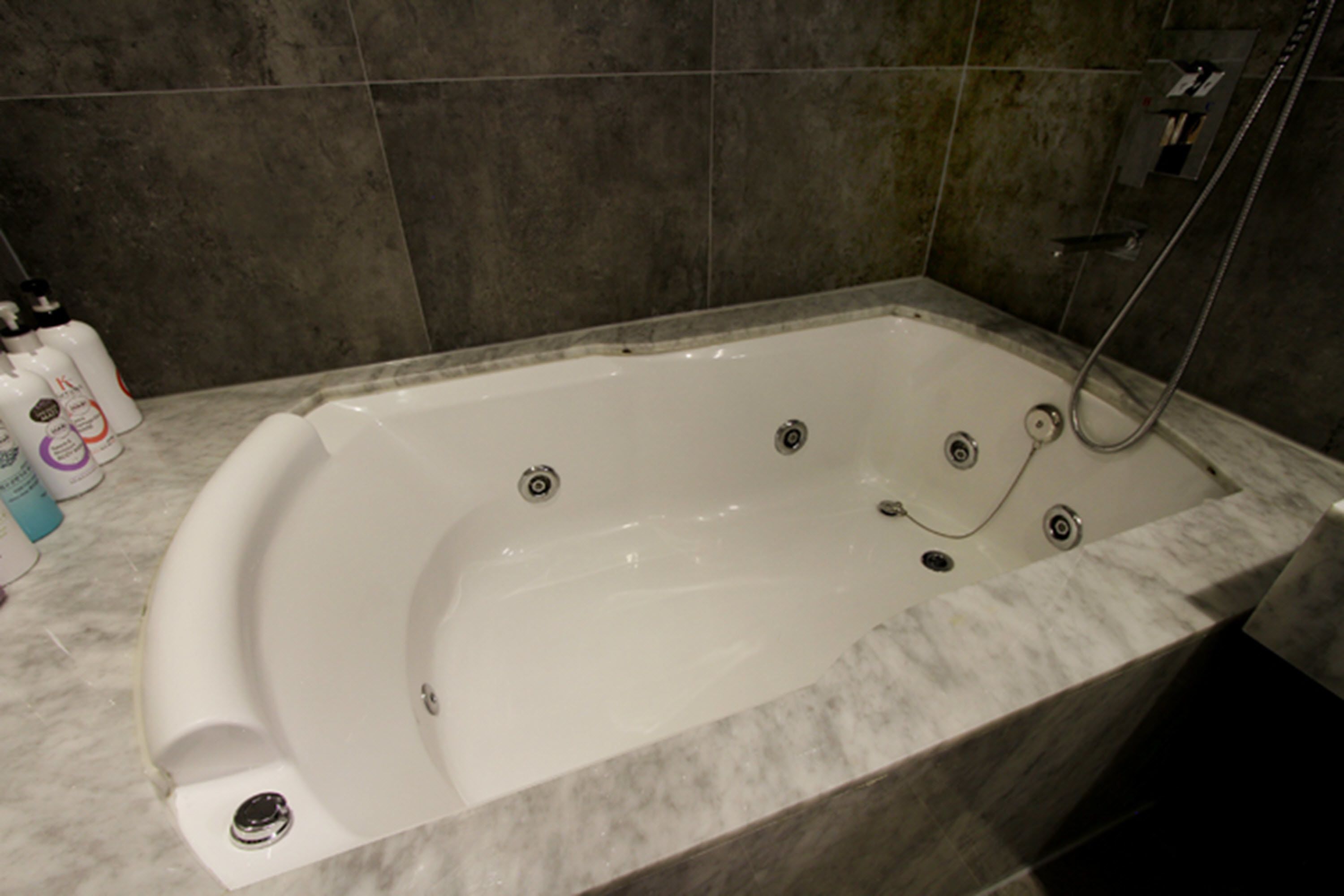 A modern bathroom with a freestanding bathtub, marble flooring, and a shower area.