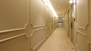 A long, narrow hallway with cream-colored walls and a tiled floor.