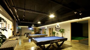 A billiards room with two pool tables, a sofa, and a small table with chairs.