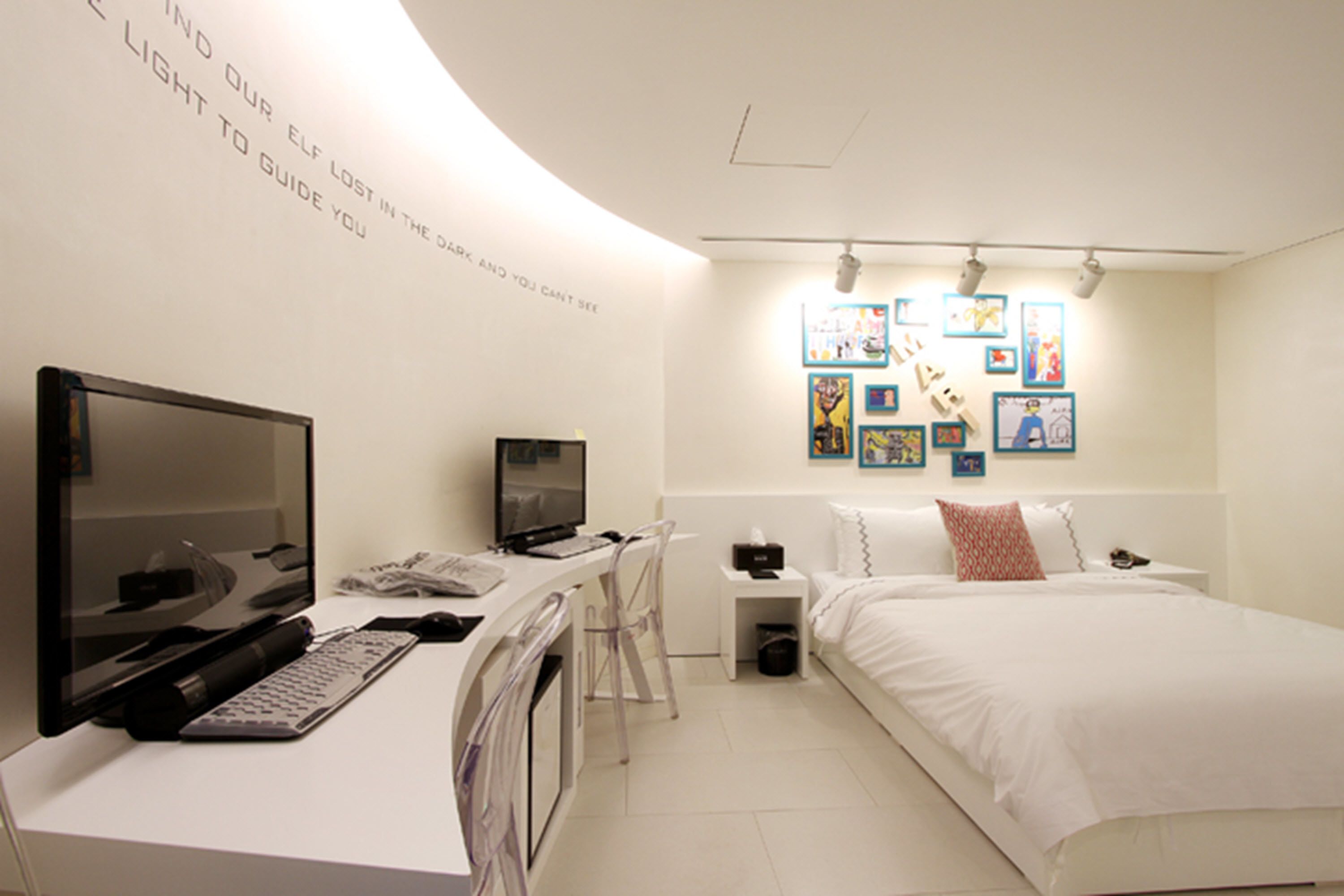 Une chambre à coucher moderne avec un bureau, un ordinateur et un lit.