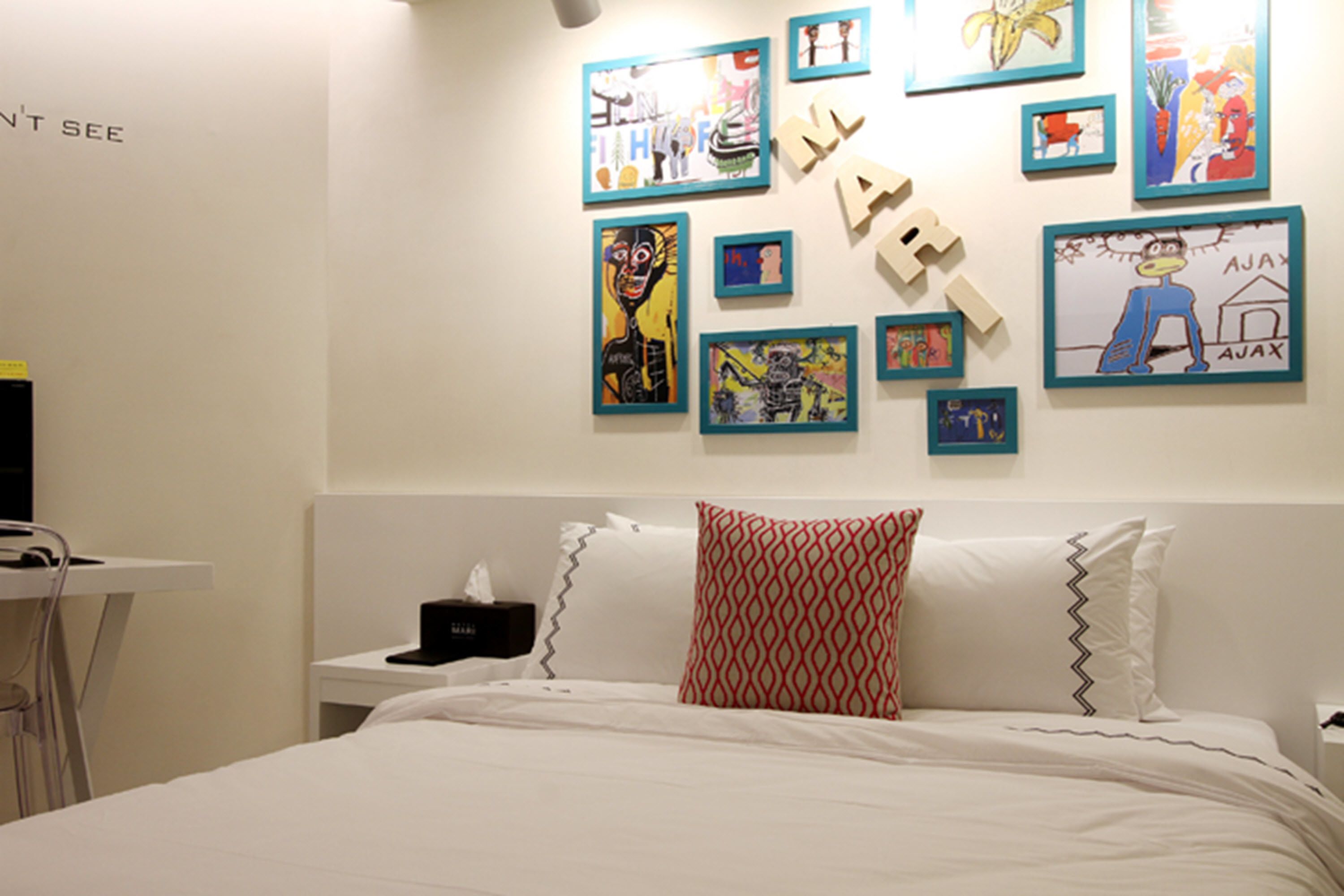 Une chambre à coucher avec un lit, des oreillers et un mur décoré de divers tableaux encadrés.