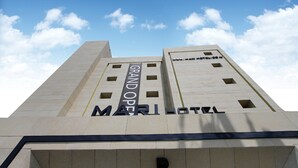 A tall hotel building with the name "Grand Open" and "Mari Hotel" visible on its facade.