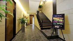 A hotel hallway with a herringbone patterned floor, a staircase, and a service sign.