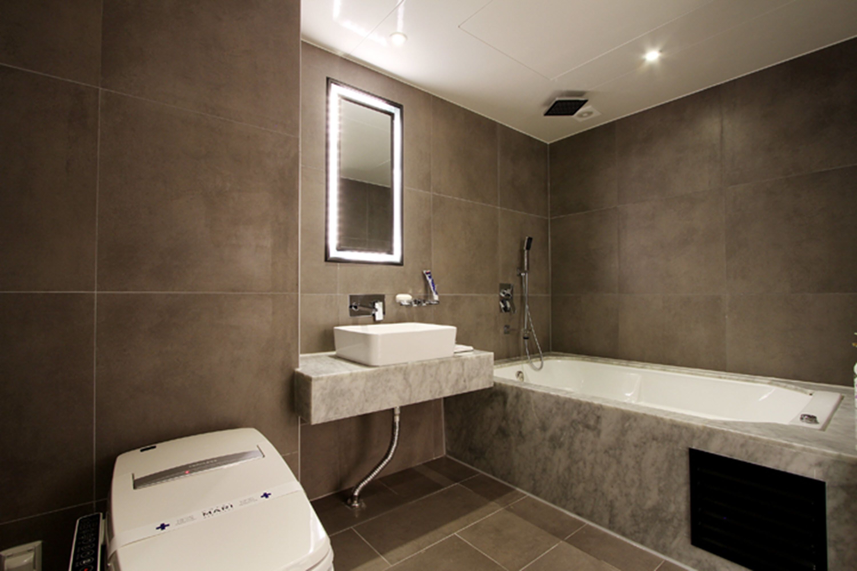 A modern bathroom with a large bathtub, a sink with a mirror above it, and a toilet.
