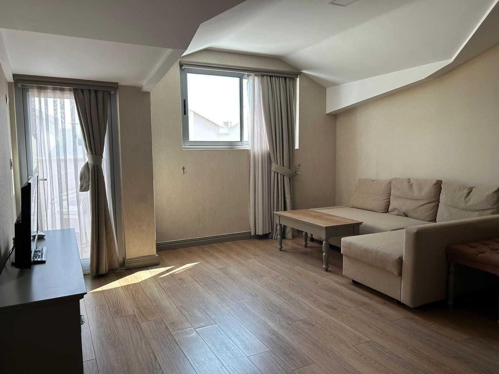 A modern living room with a sofa, a small table, and a TV.