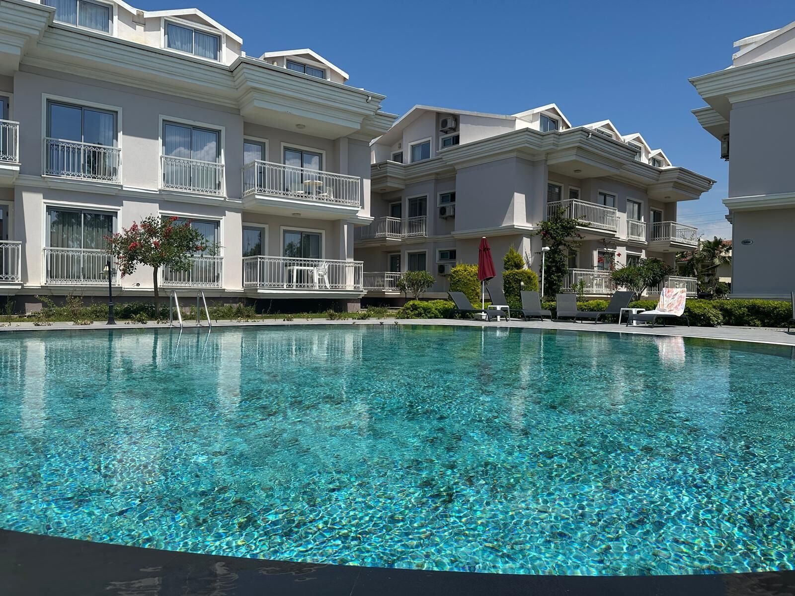 A clear swimming pool with white balconies and a clear blue sky.