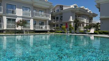 A clear swimming pool with white balconies and a clear blue sky.
