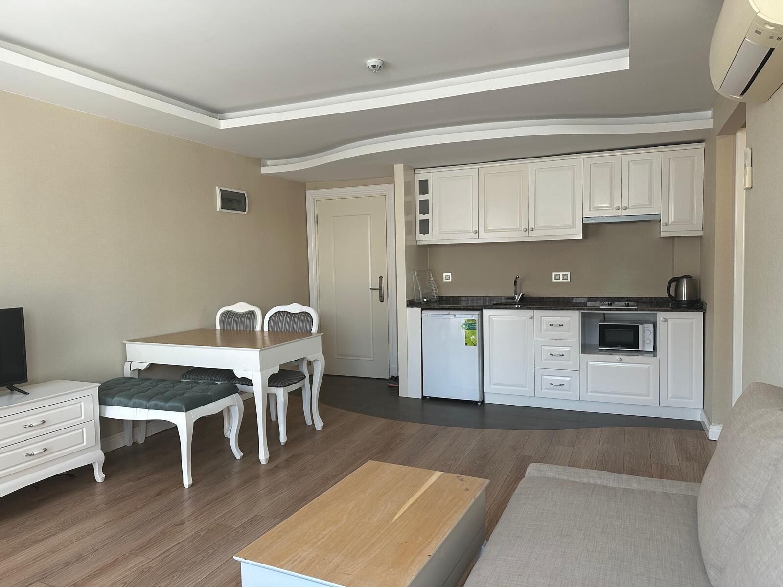 A compact living space with a dining area, kitchenette, and a sofa.