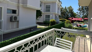 Een balkon met een witte metalen balustrade, een witte stoel en een tafel.
